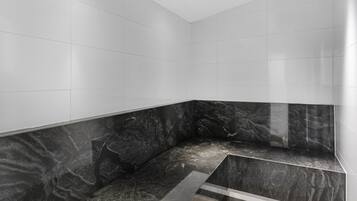 Bathroom features a minimalist design with a black countertop and white tile walls.