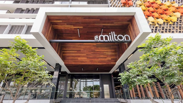 A modern building with a wooden facade and the name 'The Milton' displayed above the entrance.