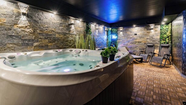 Un área de spa con hidromasaje, asientos y paredes de piedra.