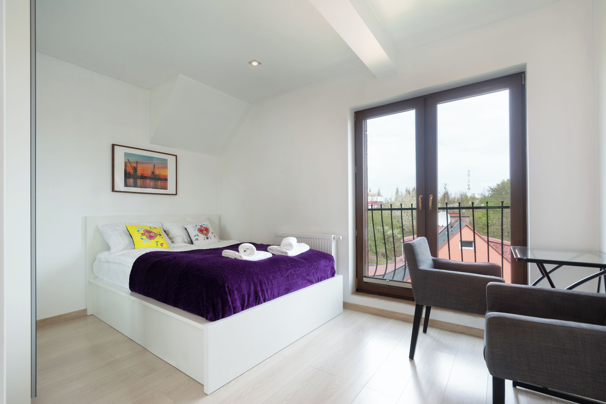 A modern bedroom with a bed, a balcony, and a chair.