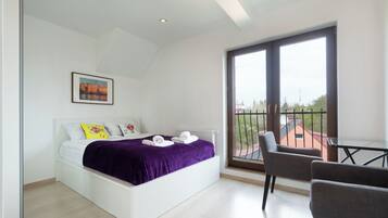 A modern bedroom with a bed, a balcony, and a chair.