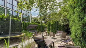 Un patio exterior con un trampolín, una zona de estar y un edificio de vidrio al fondo.