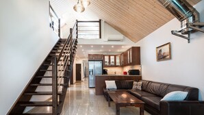 Un espacio de estar moderno con una escalera, una cocina y una zona de asientos.