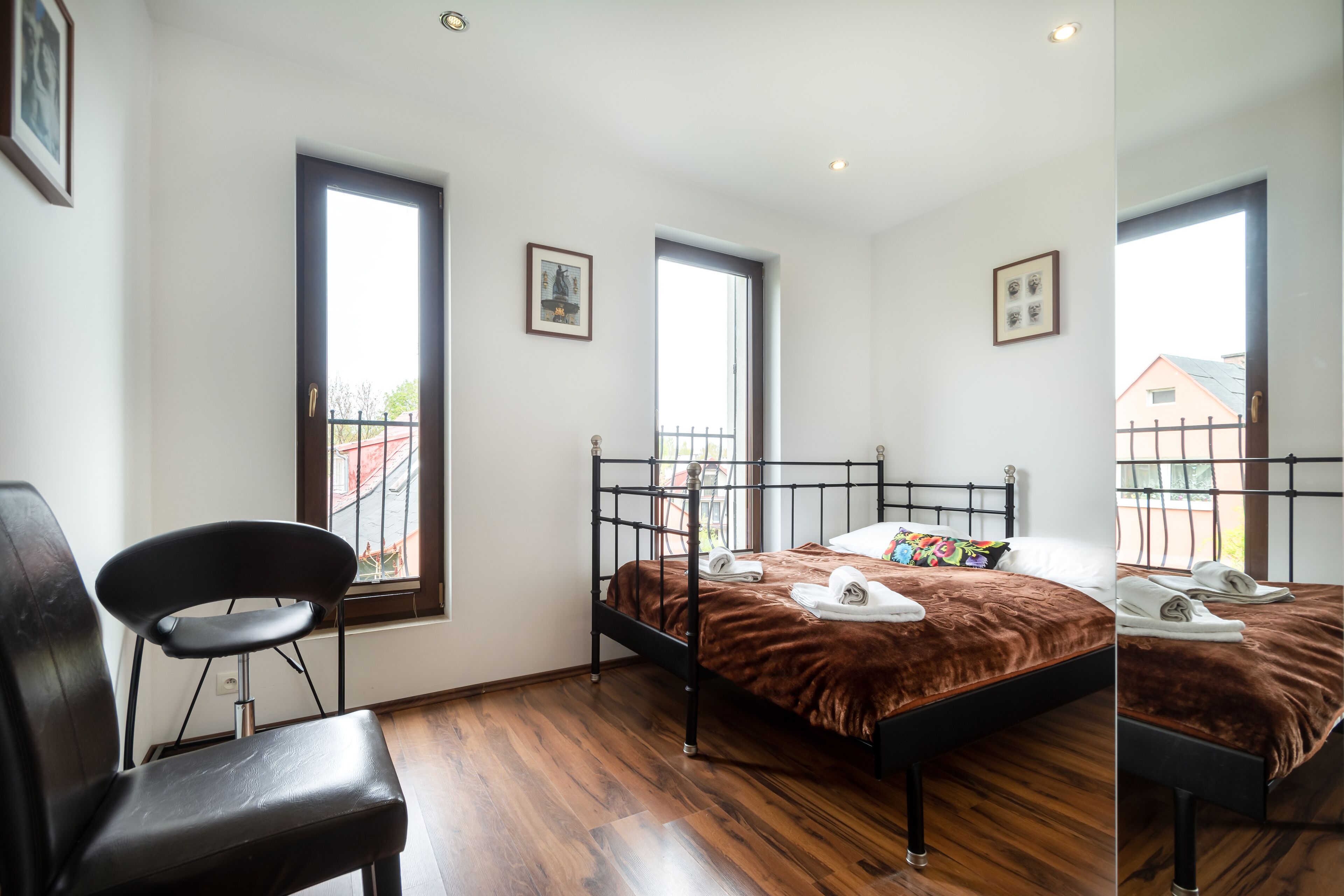 Une chambre à coucher avec un lit, une chaise et deux fenêtres.