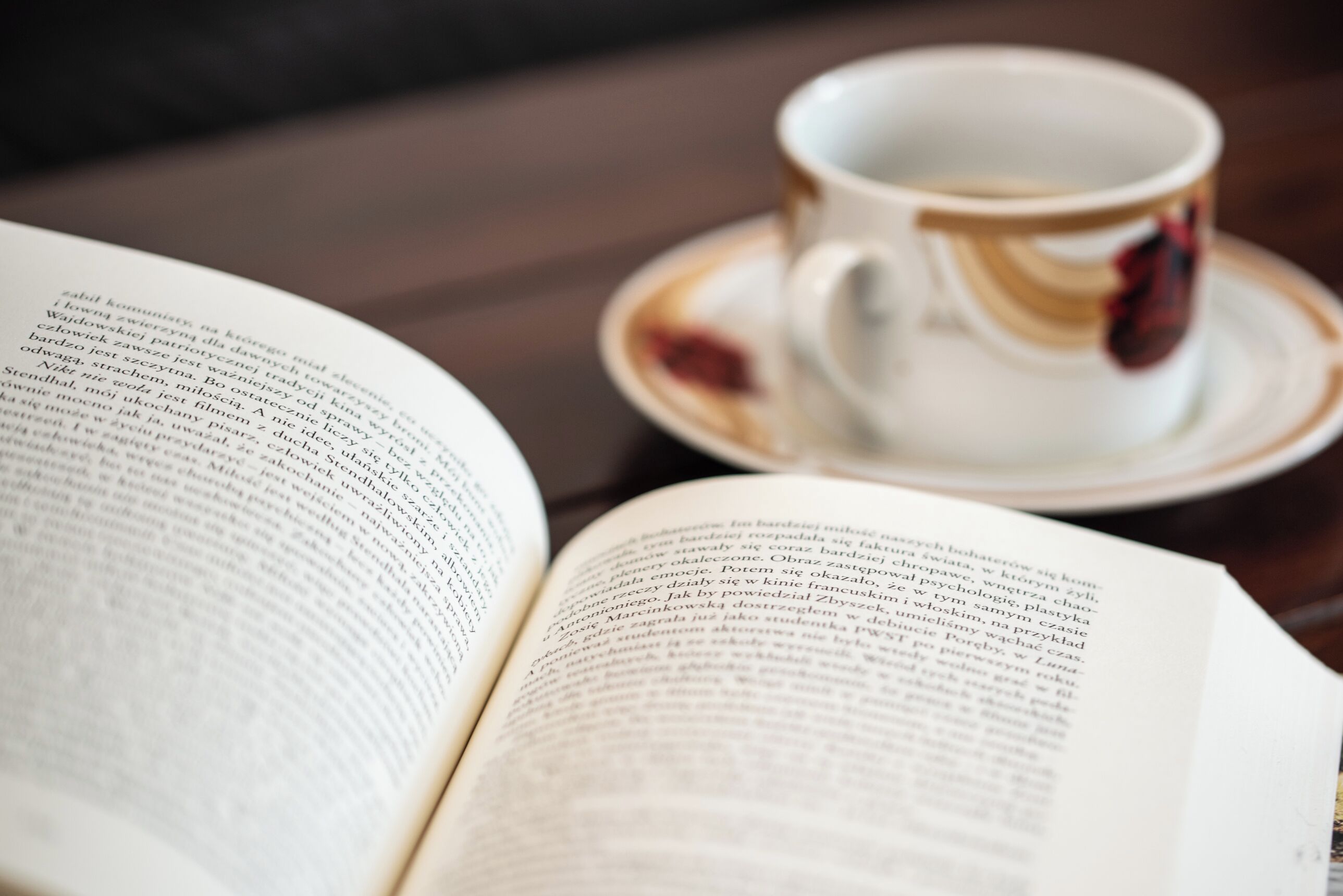Un libro abierto sobre una mesa, con una taza y un platillo a un lado.