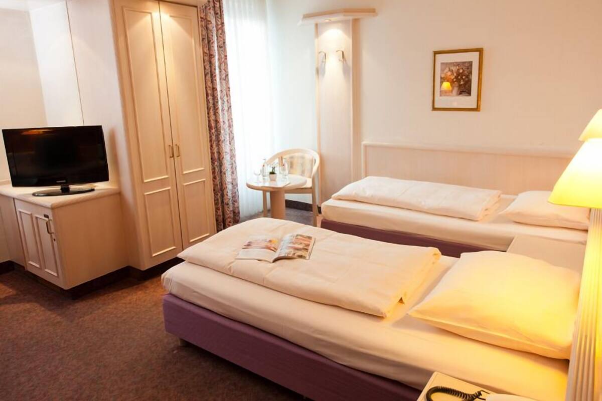 A hotel room with two beds, a television, a desk, and a chair.