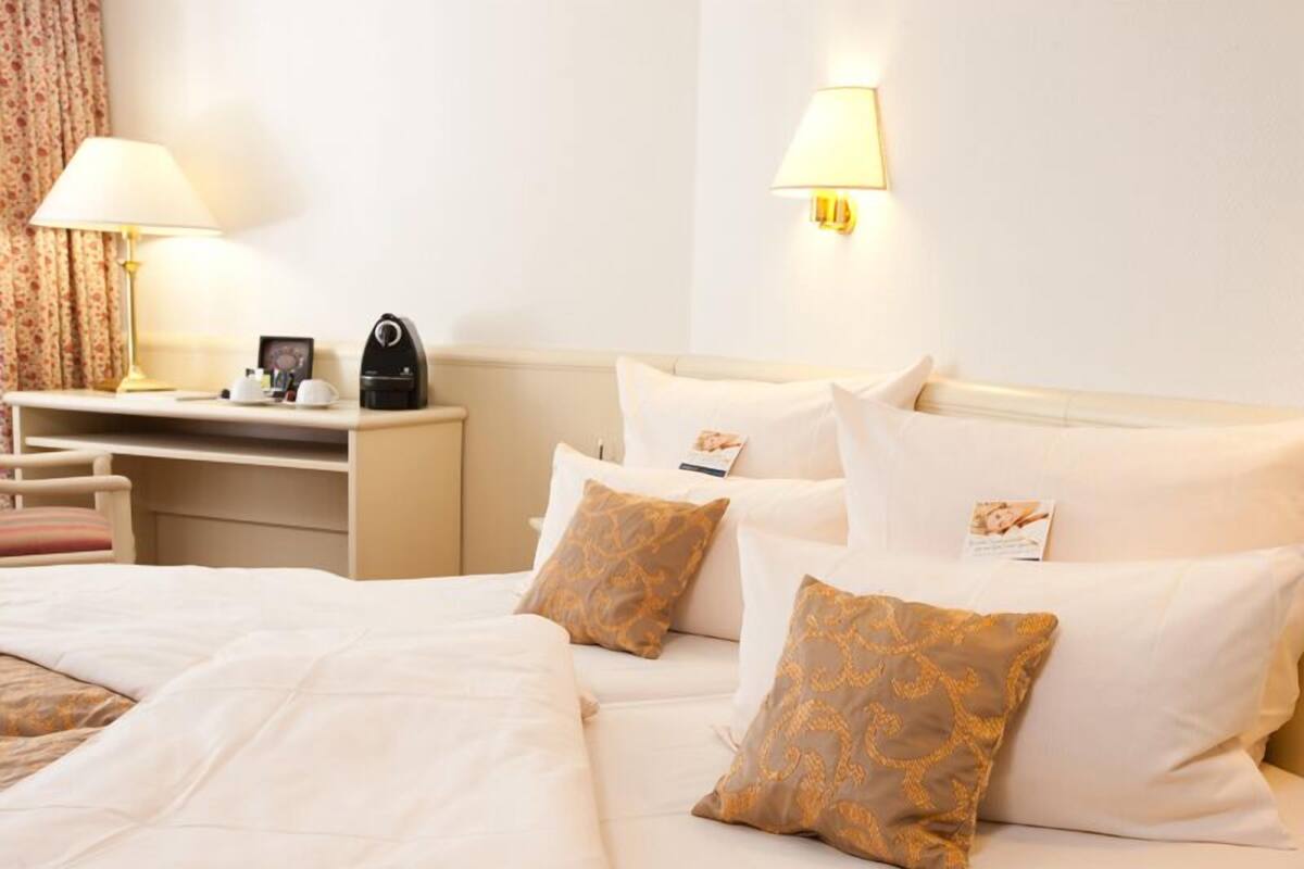 A hotel room with a bed, a desk, and a lamp.