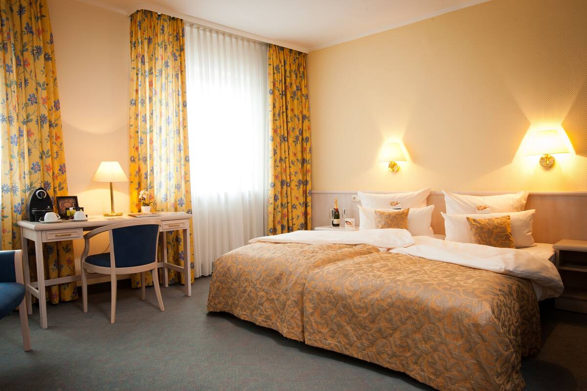 A hotel room with a bed, a desk, a chair, and a nightstand.