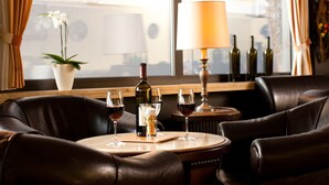A cozy seating area with leather chairs and a round wooden table, featuring a bottle of wine and glasses. - Hoteltraube Rudesheim (Ruedesheim am Rhein)