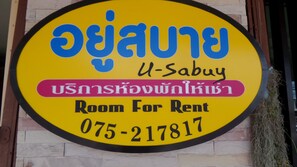 A yellow circular sign with Thai text and English "Room For Rent" indicating a rental property. - U Sabuy Mansion Trang (Trang)