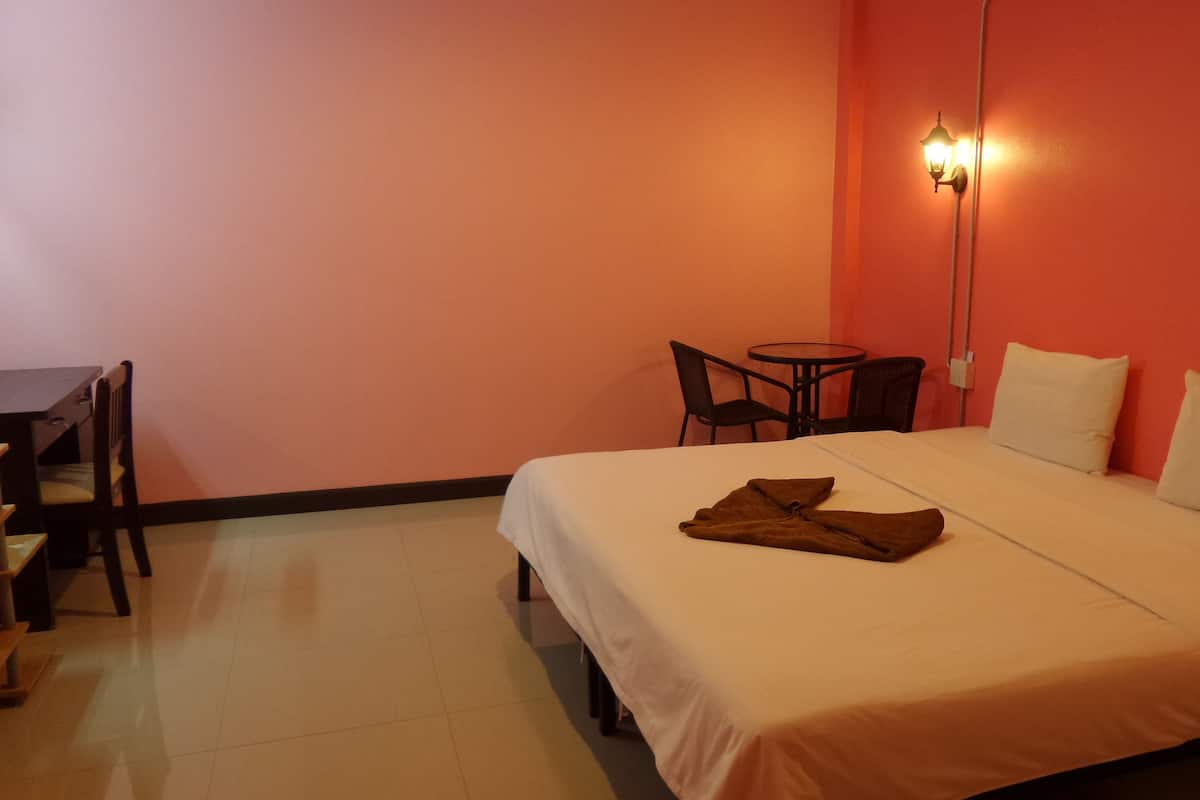 A hotel room with a bed, a desk, and two chairs.