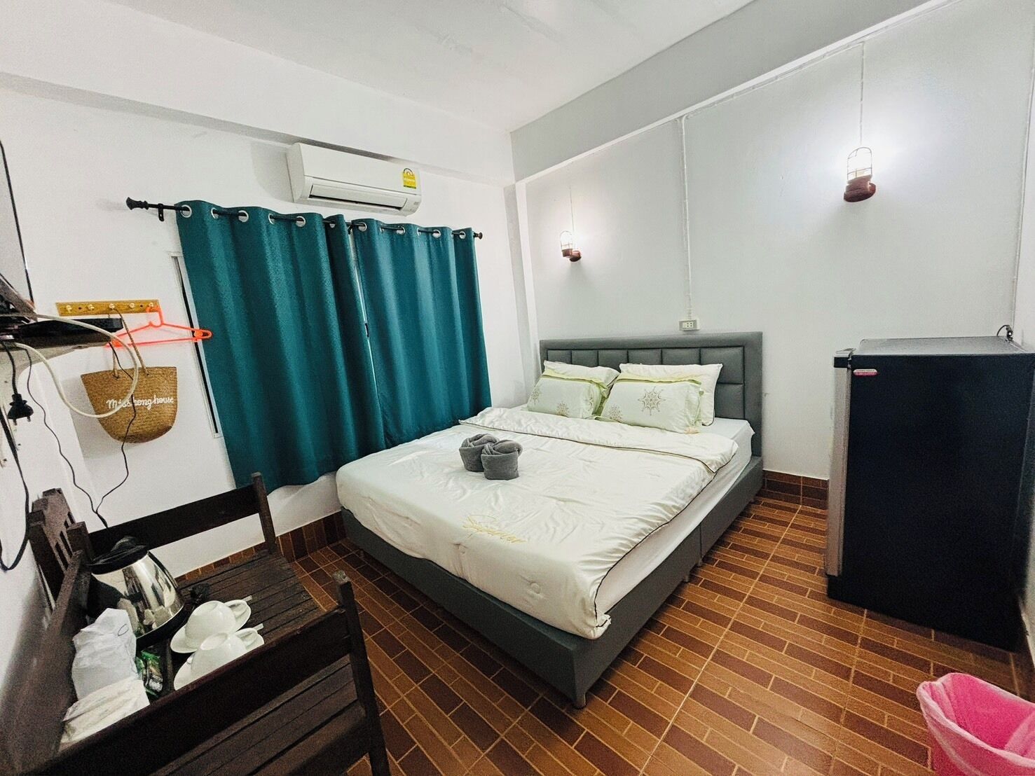 Un dormitorio con cama, armario, escritorio y una cesta colgante.
