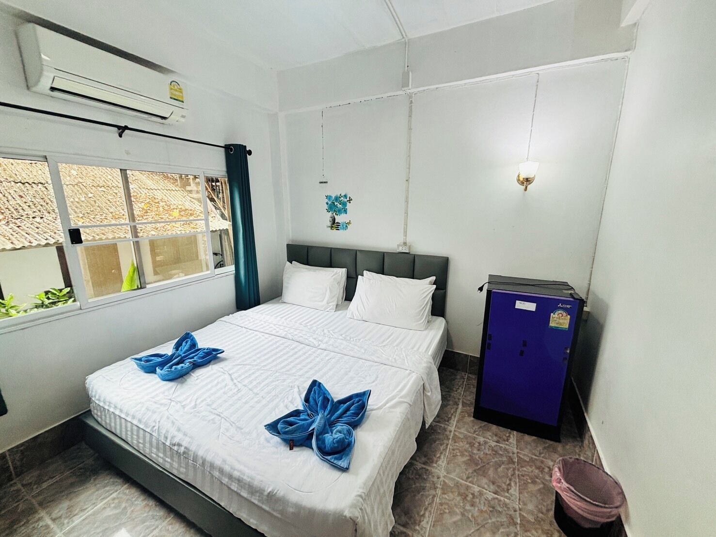 Una habitación de hotel con cama, armario y ventana.