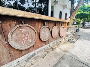 A wooden wall with circular plaques labeled "MISS," "HONG," and "HOUSE." - Miss Hong House (Rayong)