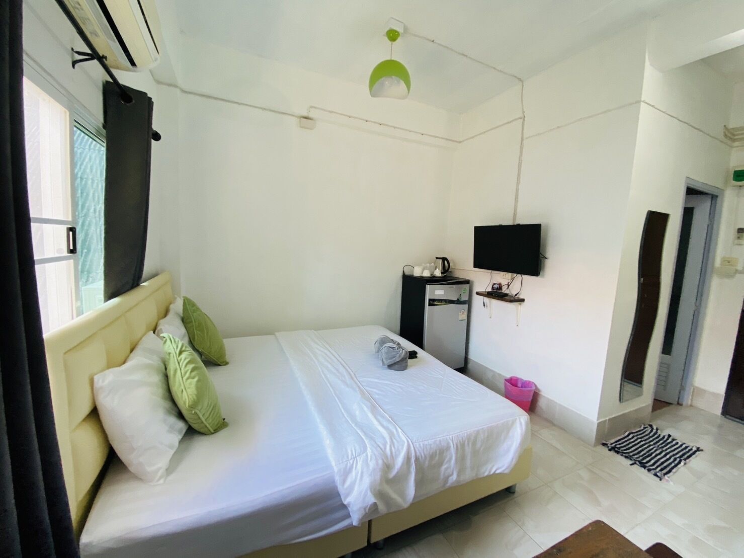 Un dormitorio con cama, escritorio, televisor y refrigerador.