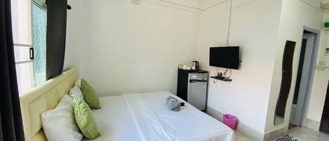 Un dormitorio con cama, escritorio, televisor y refrigerador.