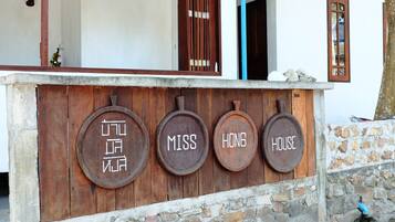 Un letrero de madera con las palabras 'MISS', 'HONG' y 'HOUSE' en la fachada de un edificio.