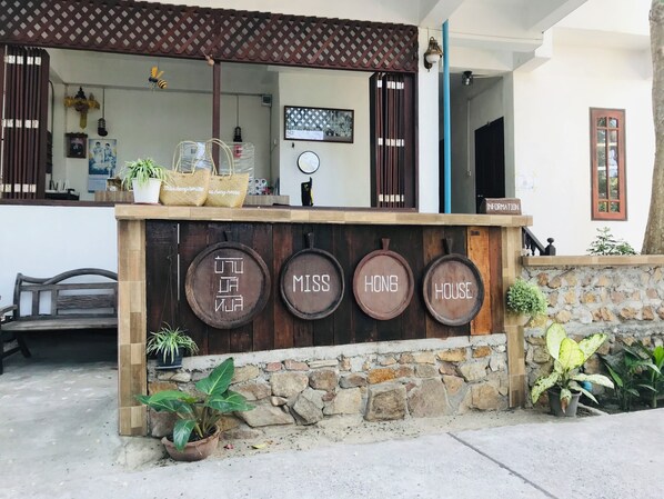 Una recepción con pared de piedra, listones de madera y un cartel que dice 'MISS HONG HOUSE'.