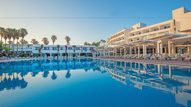 A hotel pool area with multiple lounge chairs and a clear blue pool. - Dome Beach Marina Hotel & Resort (Ayia Napa)