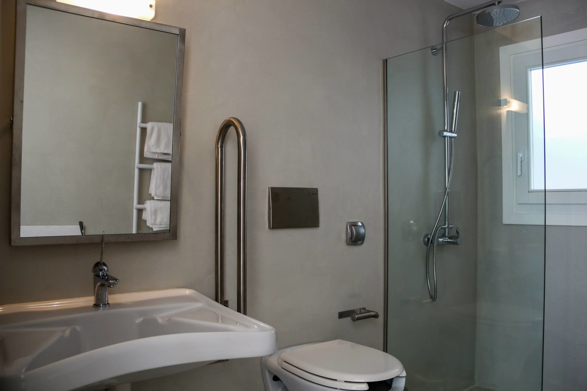 A bathroom with a white sink, a toilet, a glass-enclosed shower, and a mirror.