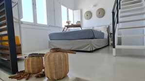 Un dormitorio con una cama, una escalera y dos cestas tejidas.