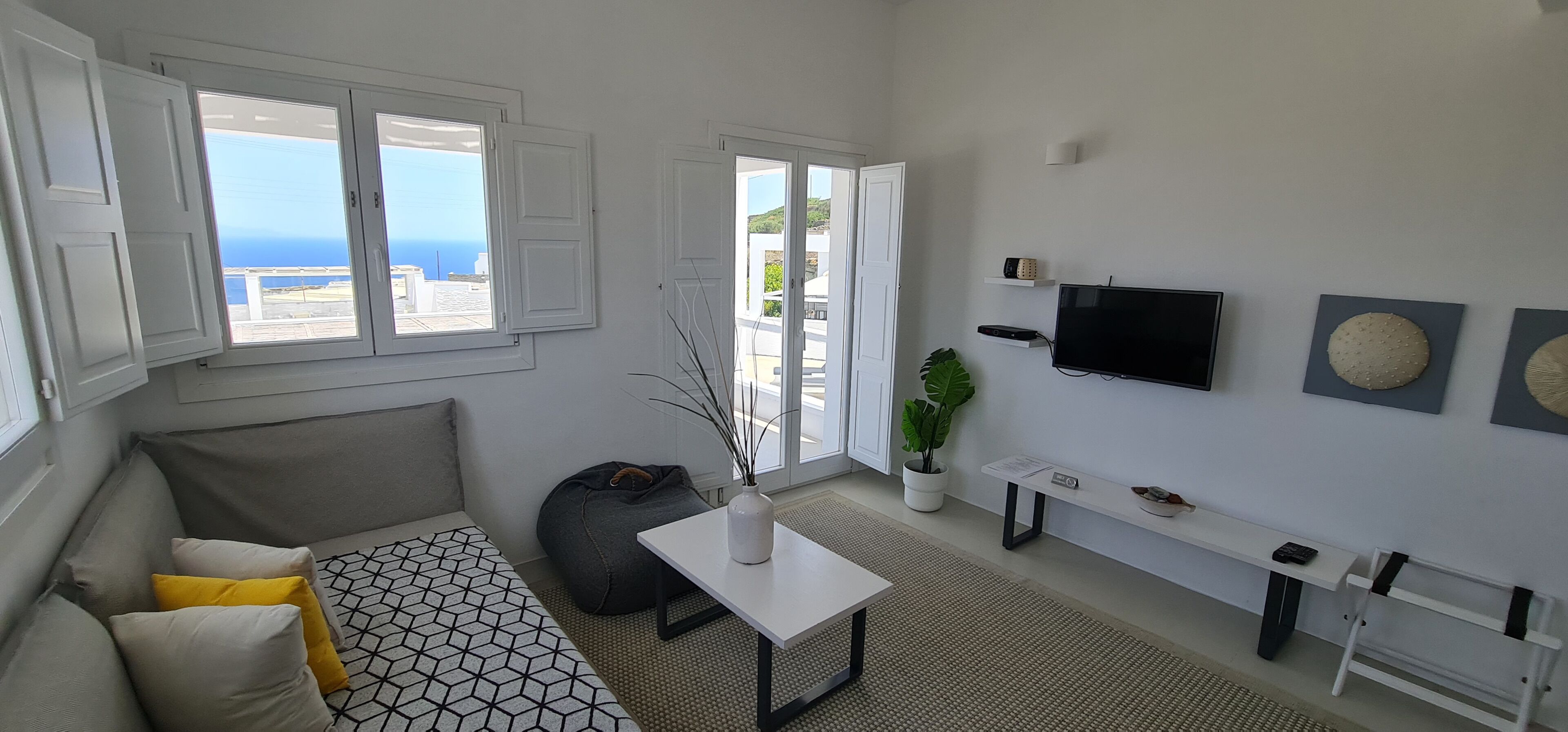 Un salon moderne avec un canapé, une table basse, un banc et un téléviseur fixé au mur.
