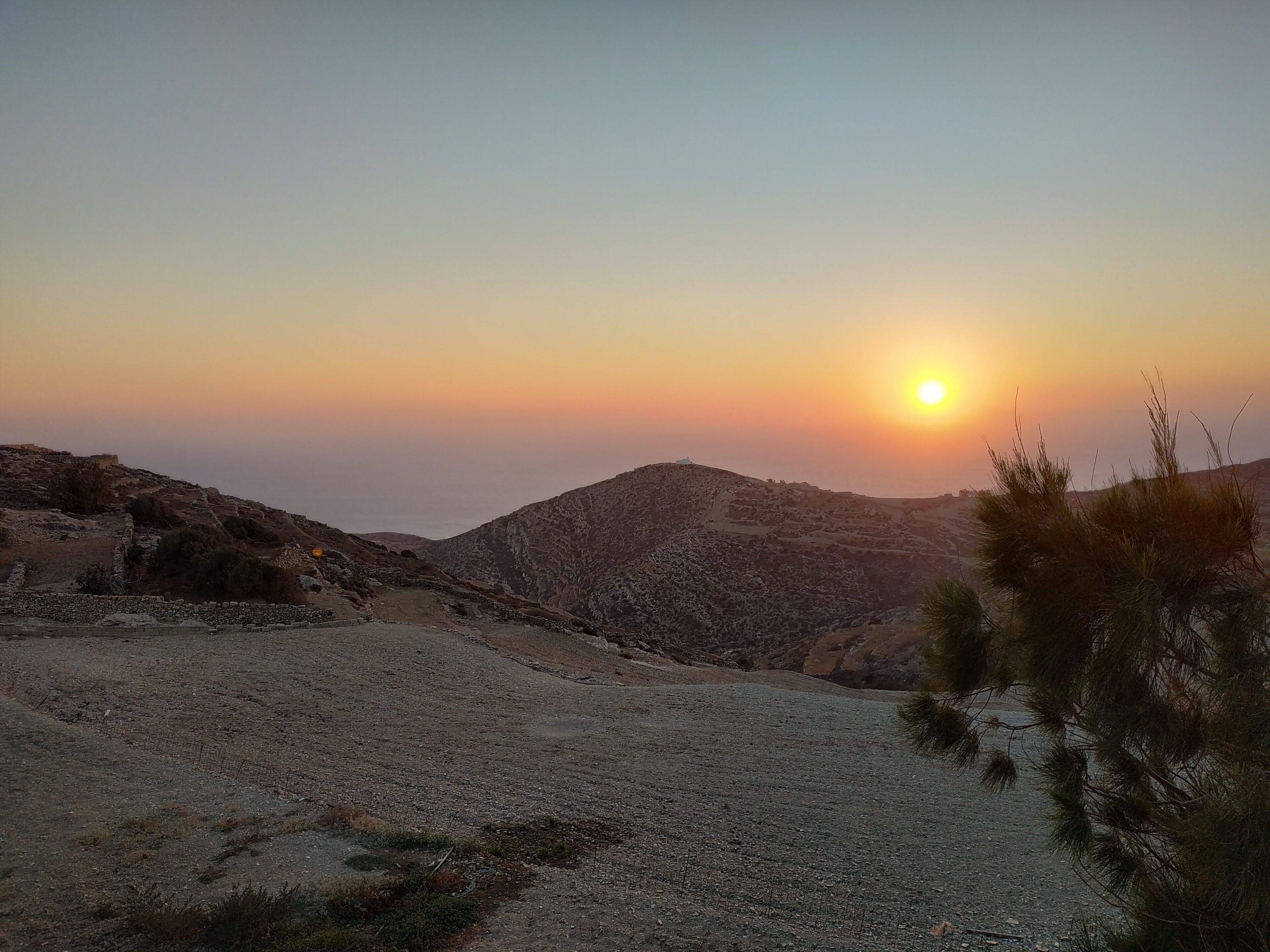 Un paysage montagneux au coucher du soleil, avec un ciel dégagé.