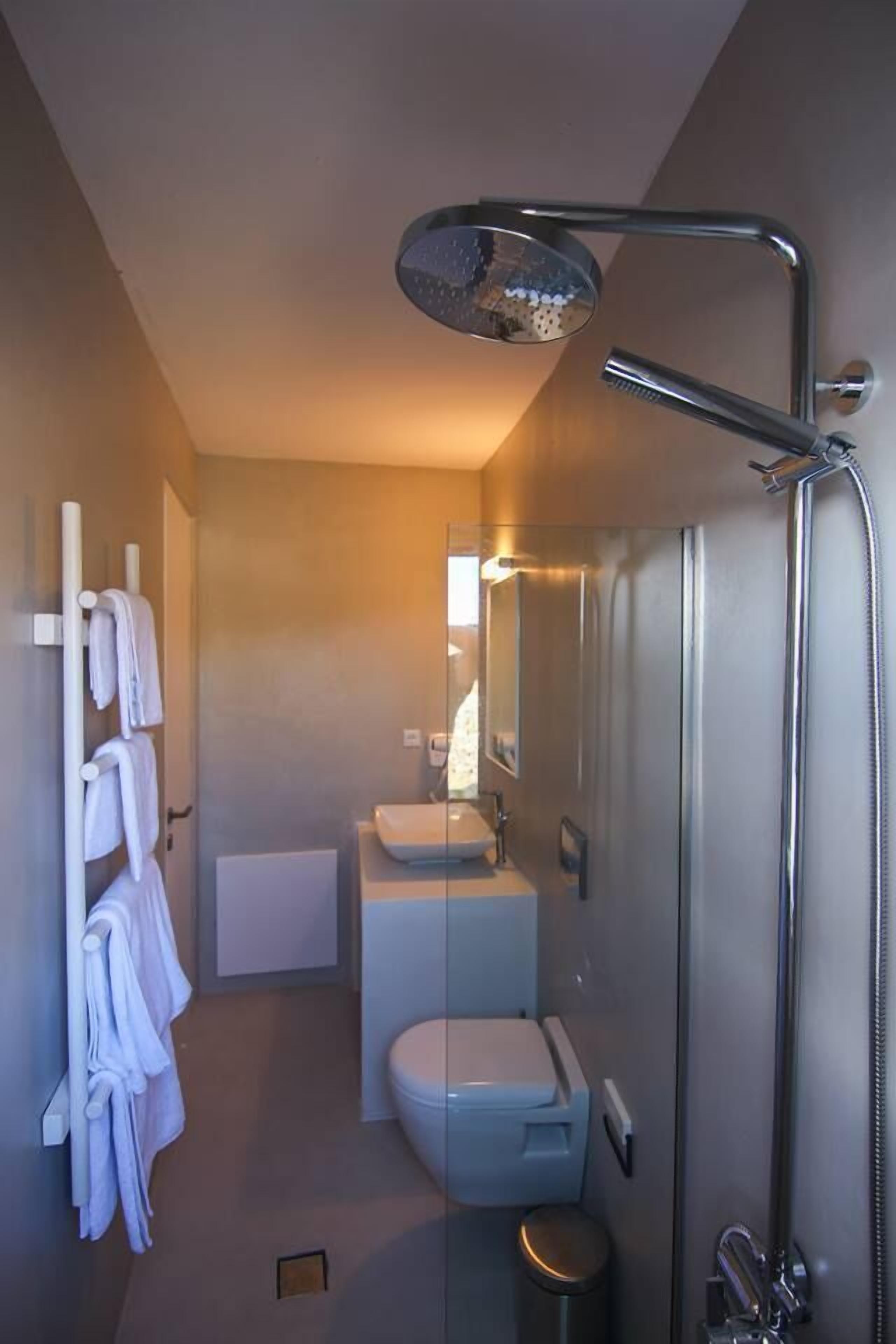 A compact bathroom with a shower, toilet, and sink.