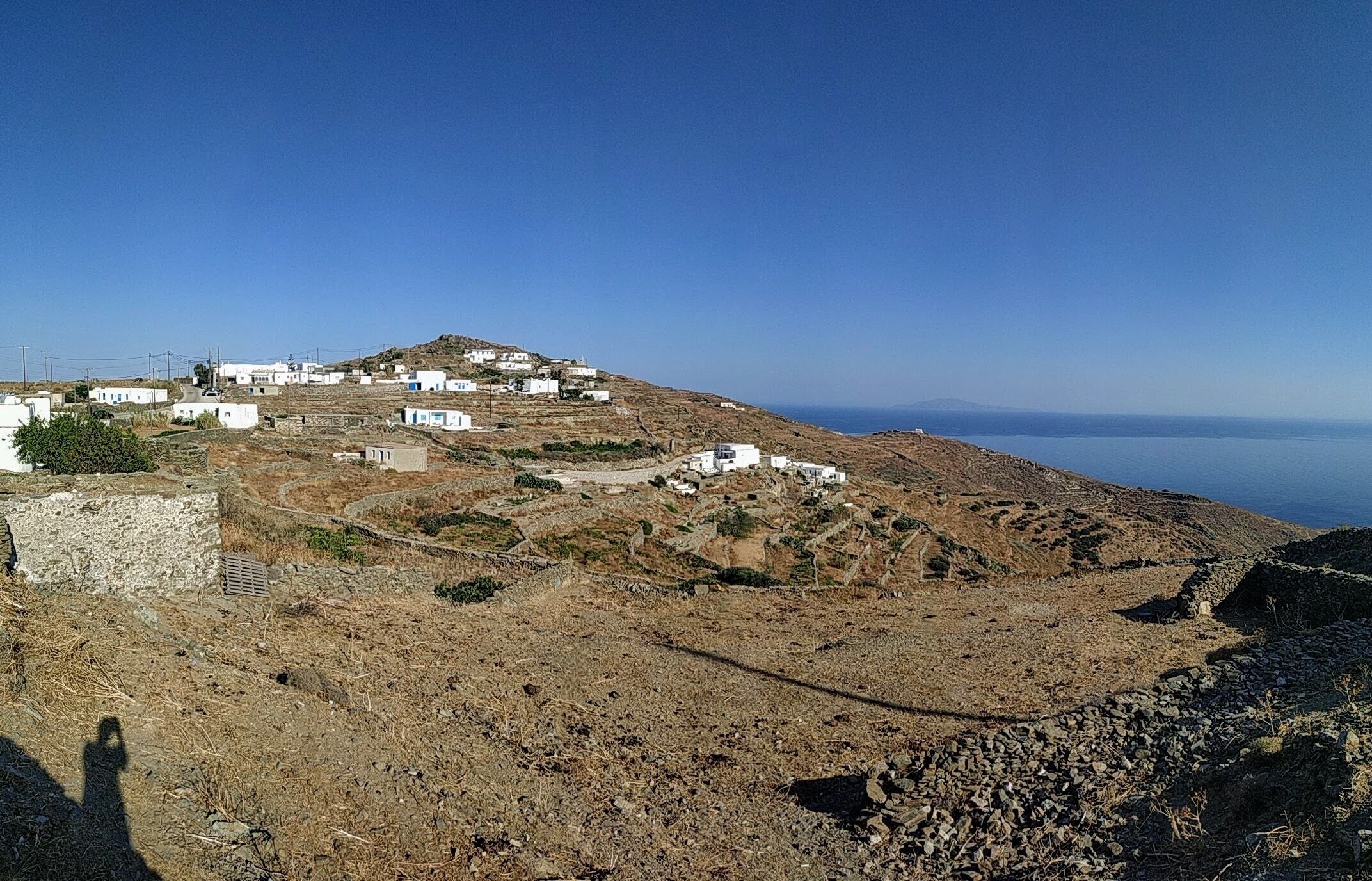 A coastal village with white buildings, rocky terrain, and a clear view of the sea.