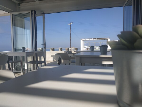Un espace extérieur moderne, aménagé avec des tables et des chaises, offrant une vue dégagée sur un ciel bleu et une perspective lointaine sur un bâtiment.