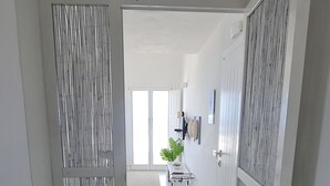 Un pasillo que conduce a una habitación con una cama, una planta en maceta y una puerta con diseño a rayas.