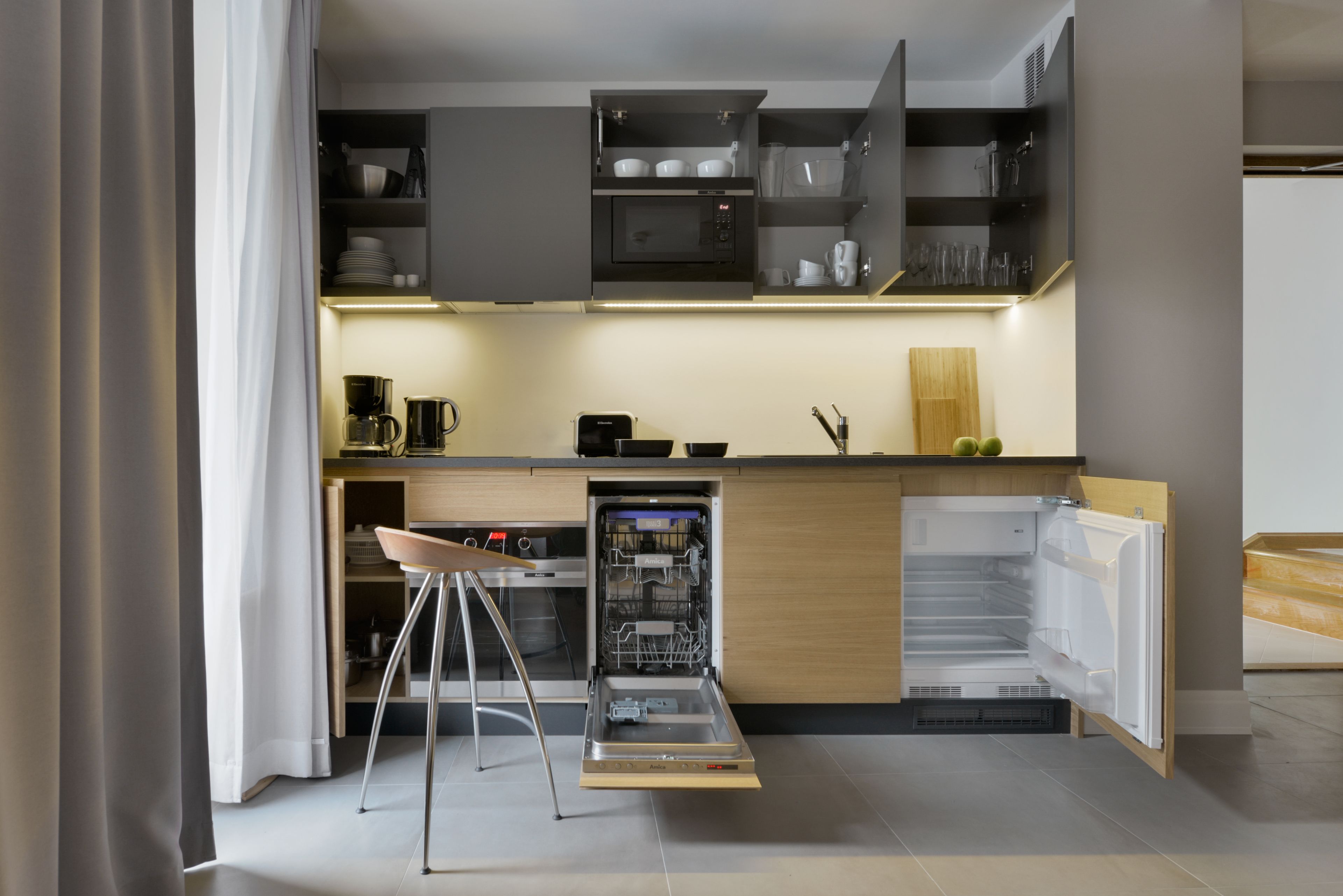 A modern kitchen with a built-in dishwasher, a coffee machine, and a wooden countertop.