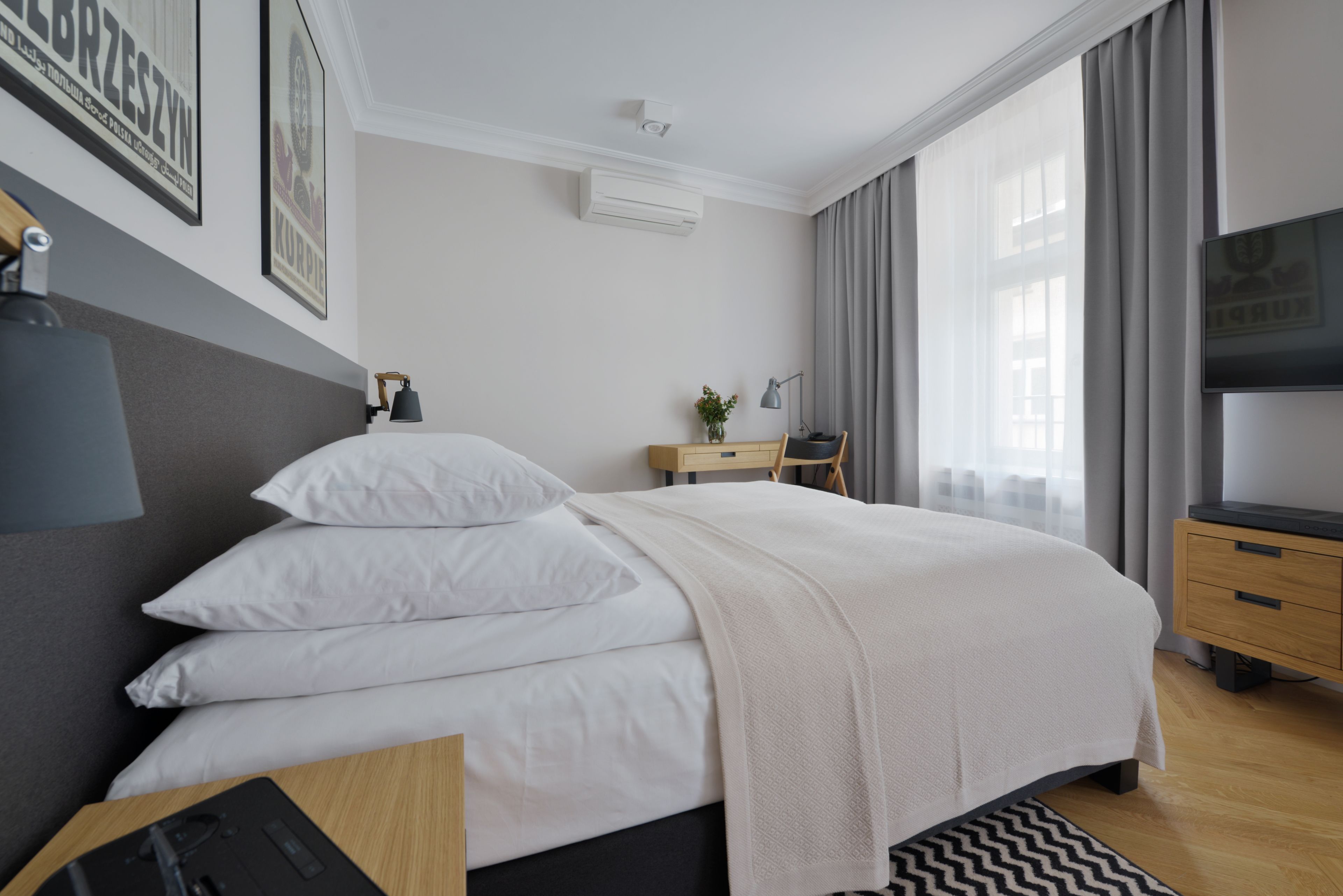 A neatly arranged bedroom with a bed, bedside table, lamp, and a TV.