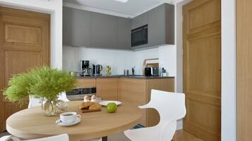 A modern kitchen with grey cabinets, a microwave, and a coffee maker. There is a dining table with chairs and a vase of green plants.