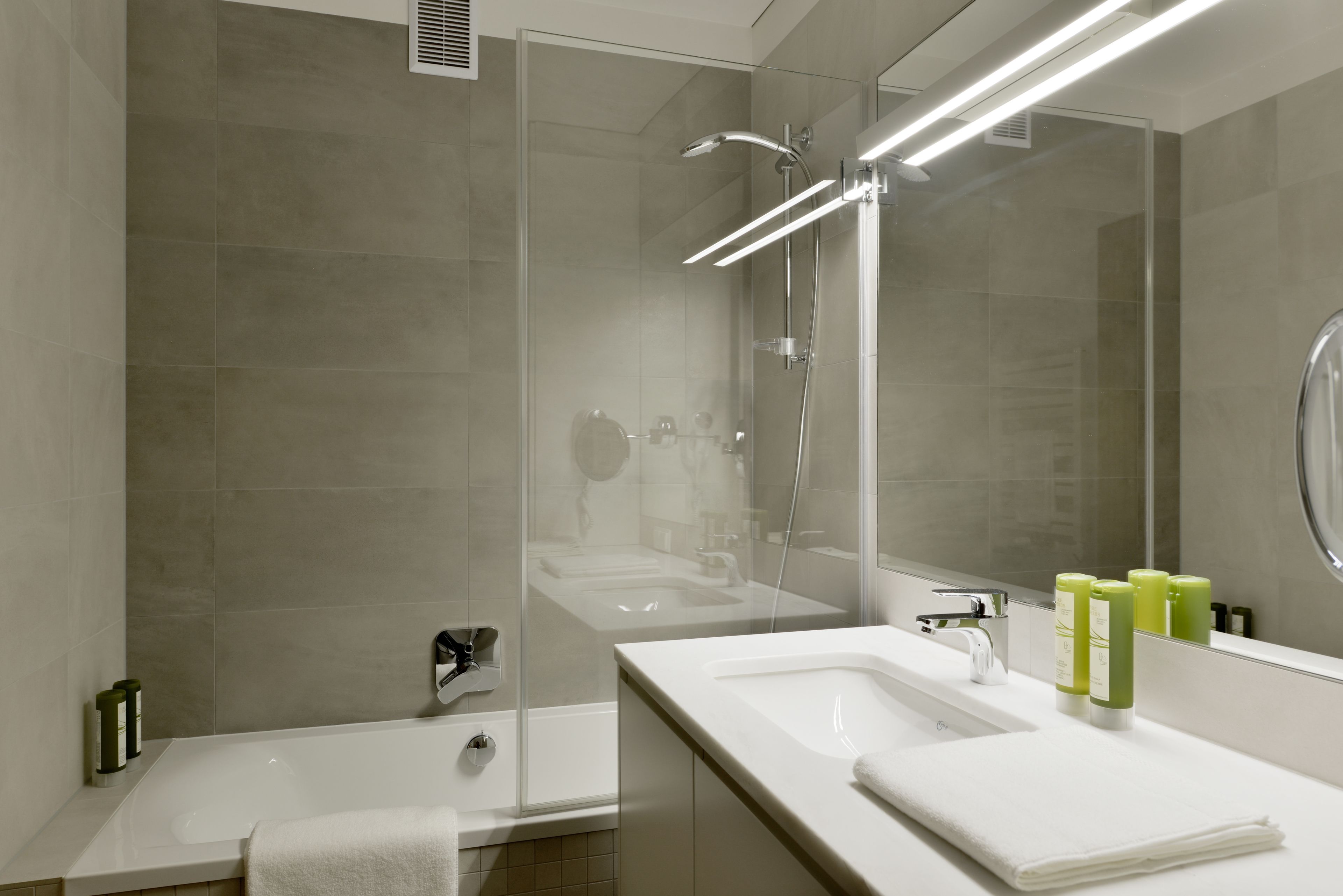 Une salle de bain moderne dotée d’une douche à parois de verre, d’une baignoire et d’un meuble-lavabo avec un miroir.