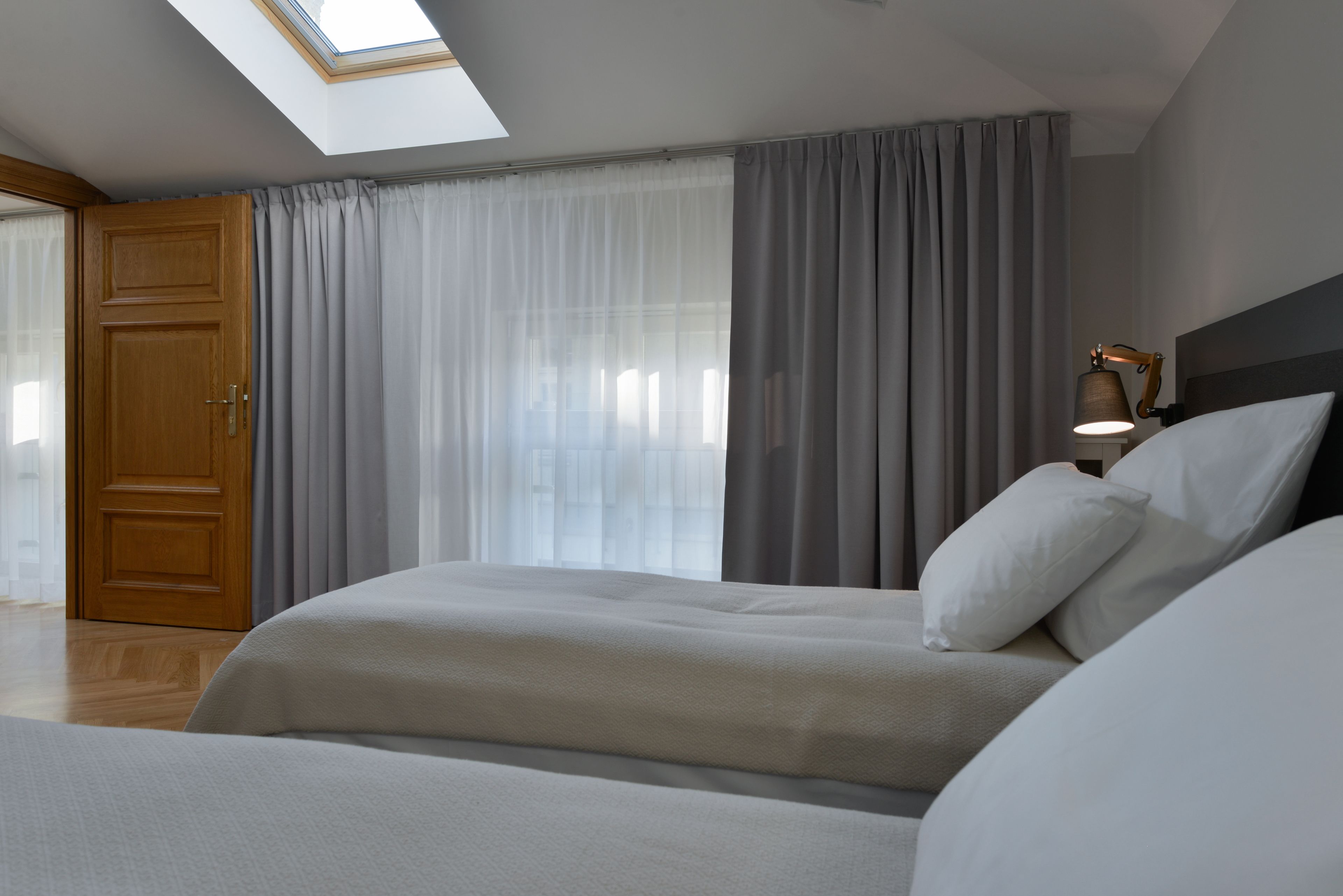 Ein Schlafzimmer mit Dachfenster, einem Bett, einem Nachttisch mit Lampe und einem Kleiderschrank.