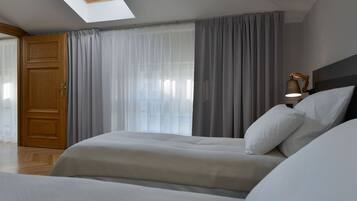 Ein Schlafzimmer mit Dachfenster, einem Bett, einem Nachttisch mit Lampe und einem Kleiderschrank.