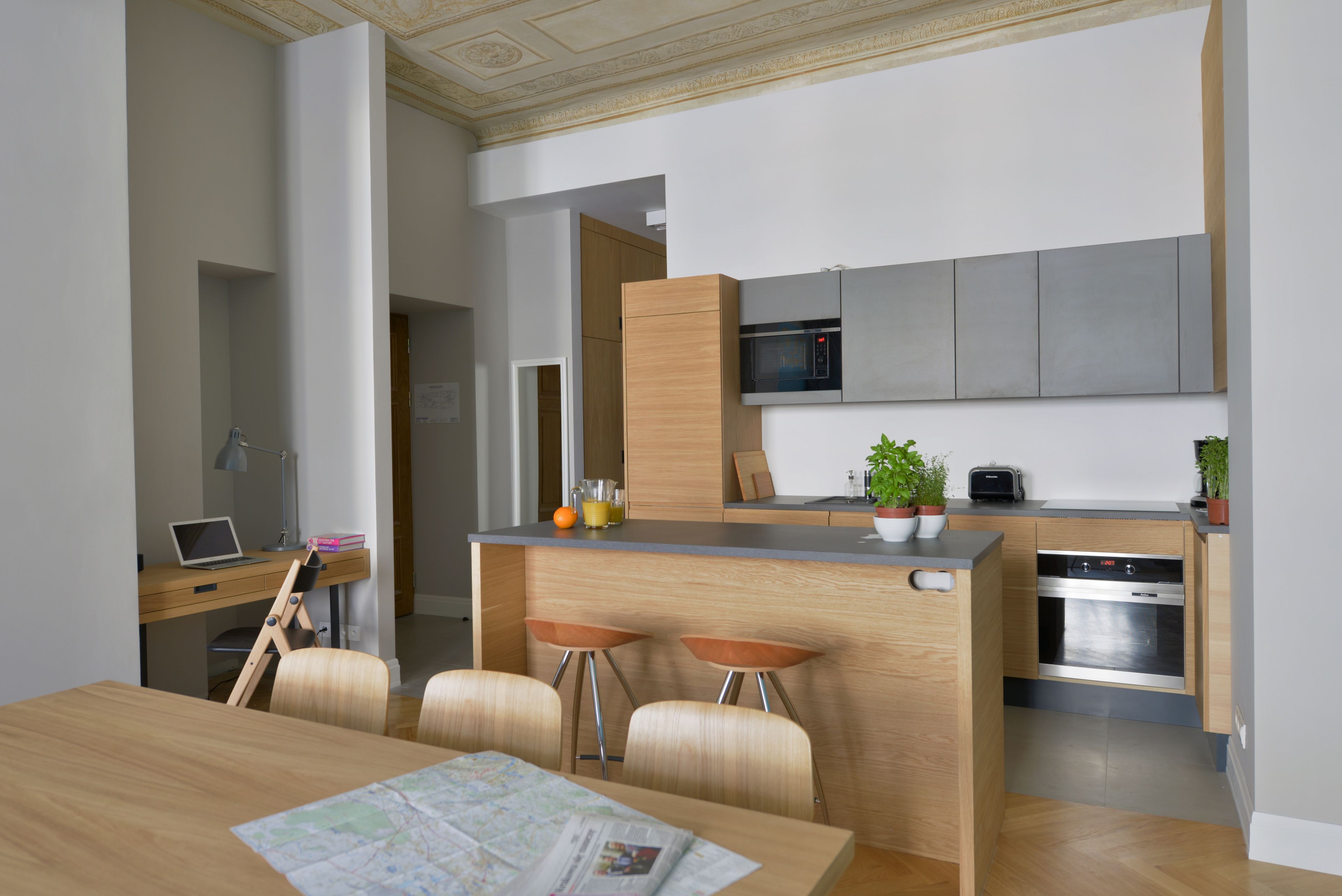 A modern kitchen with a built-in microwave, oven, and bar stools.
