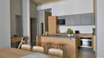 A modern kitchen with a built-in microwave, oven, and bar stools.