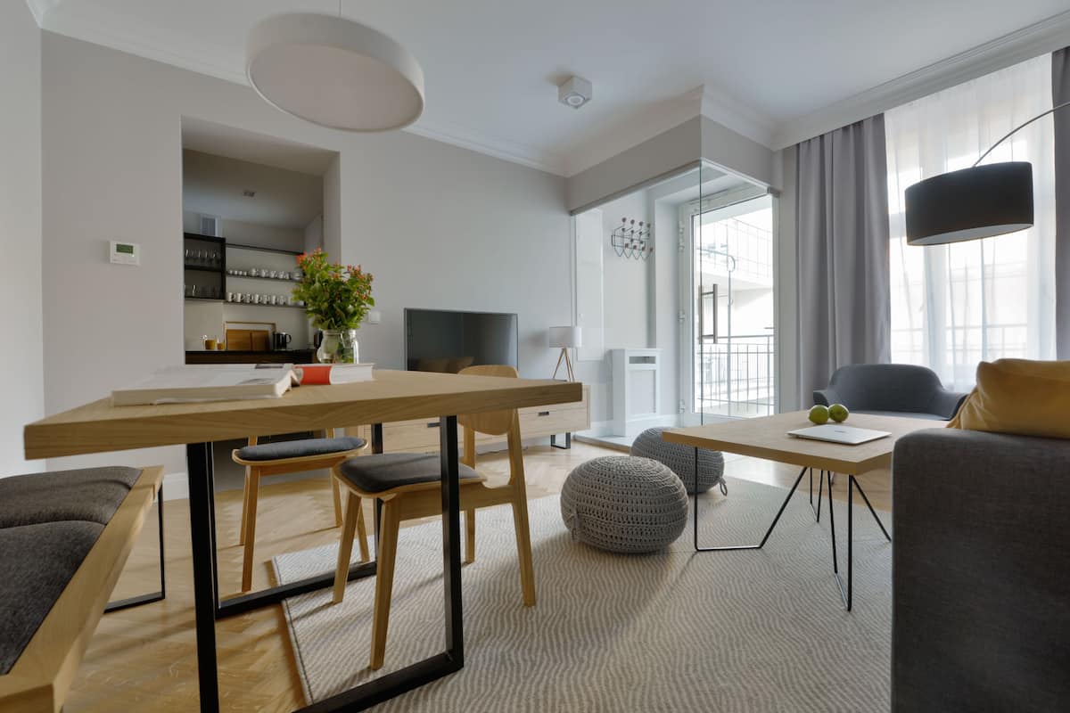 Una sala de estar moderna con comedor, televisor y un amplio ventanal con cortinas.