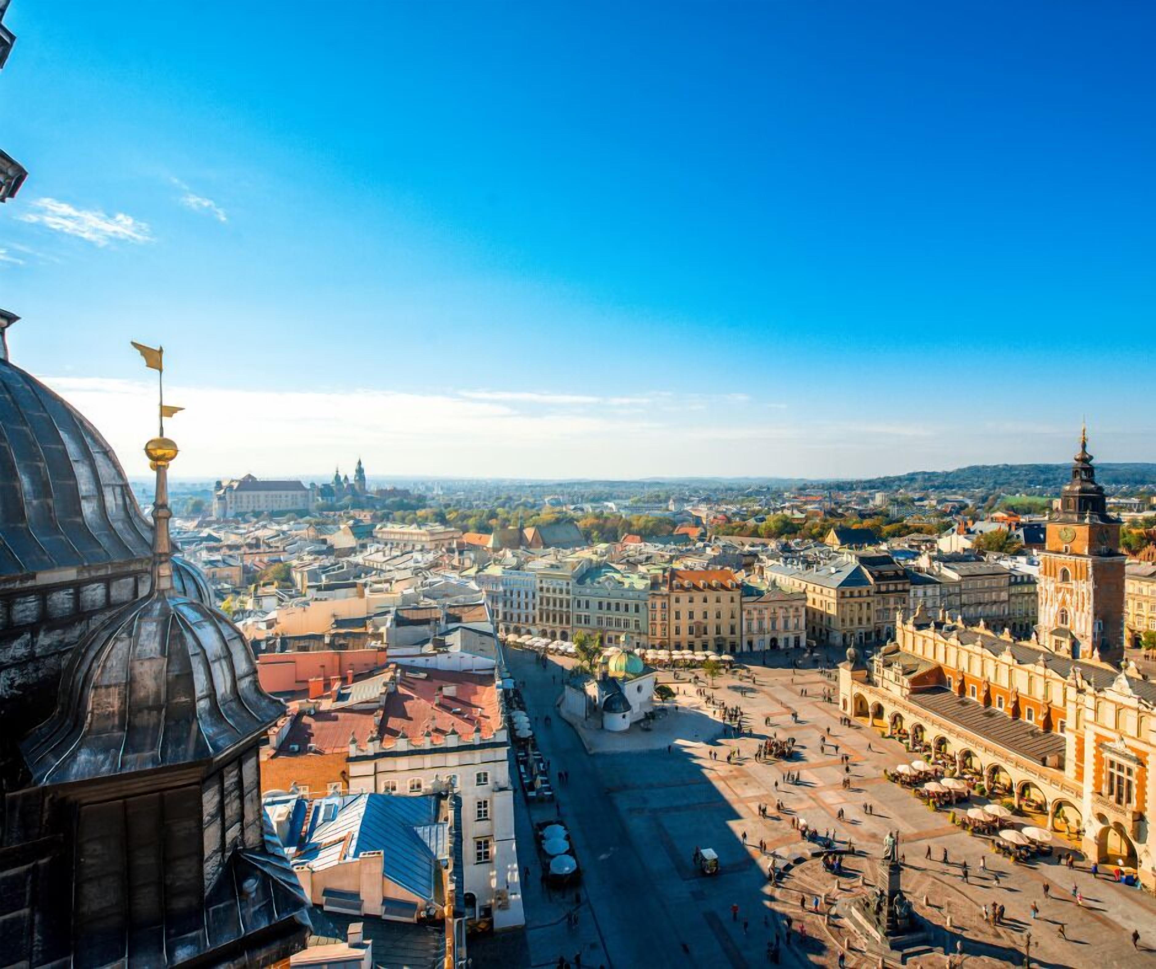 A panoramic view of a cityscape with historic architecture, including a prominent dome and a large square with a statue.
