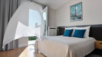 Une chambre d’hôtel moderne avec un grand lit, un balcon doté d’un auvent blanc et une affiche accrochée au mur.