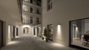 Un estrecho patio empedrado con un arco central, flanqueado por edificios con balcones y ventanas grandes.