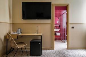 Ein Hotelzimmer mit Schreibtisch, Stuhl, Fernseher und einem kleinen schwarzen Kühlschrank.