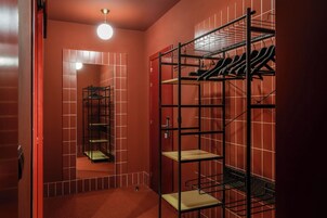 Ein kleiner Raum mit einem Spiegelkleiderschrank und einem Metallregal mit Haken.