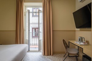 Ein Hotelzimmer mit Bett, Schreibtisch mit Stuhl, Fernseher und Blick auf den Balkon.