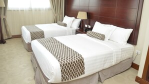 A hotel room with two beds, each with a headboard, a bedside table with a lamp, and a window with curtains. - Addissinia Hotel (Addis Ababa)