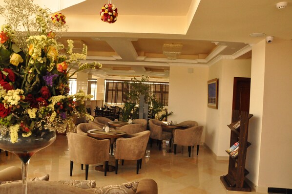 A spacious lobby with comfortable seating, a large floral arrangement, and a wooden bookshelf.