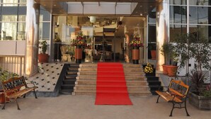 The entrance of Addissima Hotel with a red carpet, steps, and potted plants. - Addissinia Hotel (Addis Ababa)