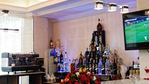 A bar area with a coffee machine, a variety of liquor bottles, and a television displaying a sports game. - Addissinia Hotel (Addis Ababa)